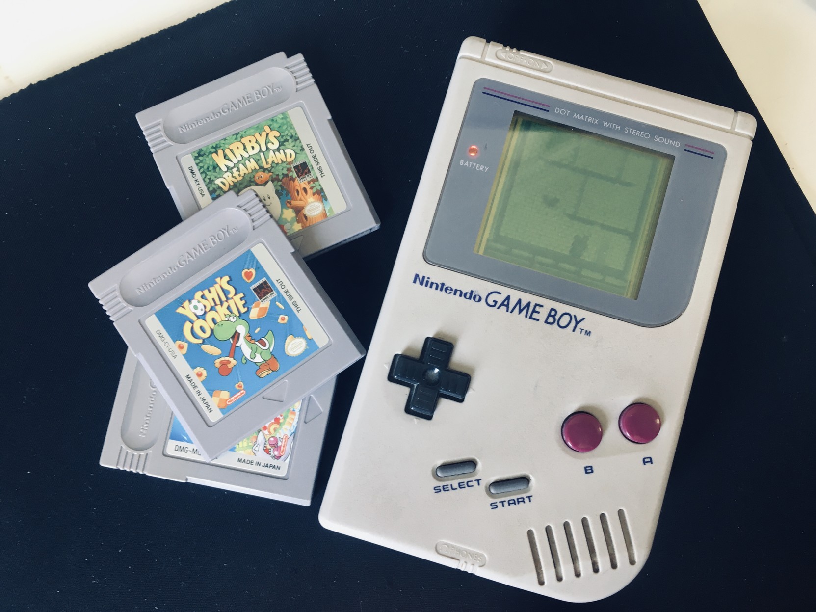 A hand held Game Boy console with game cartridges